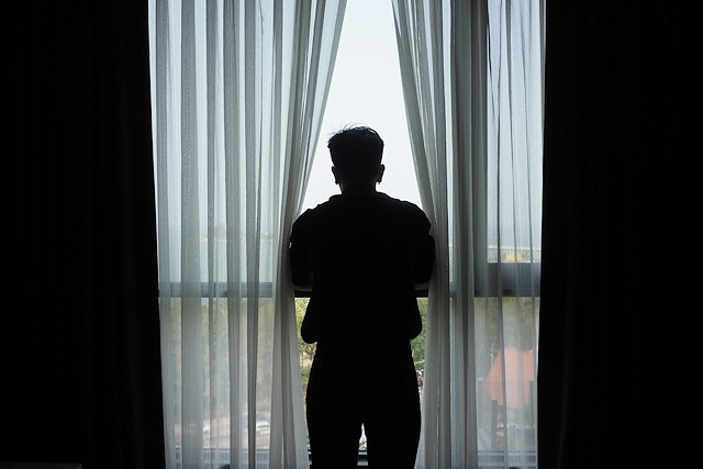 Silhouette of man standing at the window in the dark room