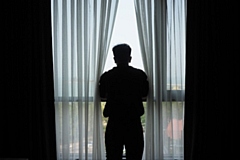 Silhouette of man standing at the window in the dark room